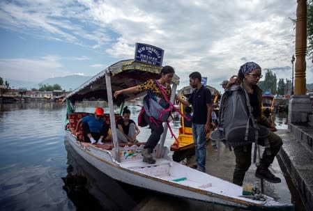 Foreign tourists disembark from a boat on the banks of Dal Lake as they prepare to leave Srinagar