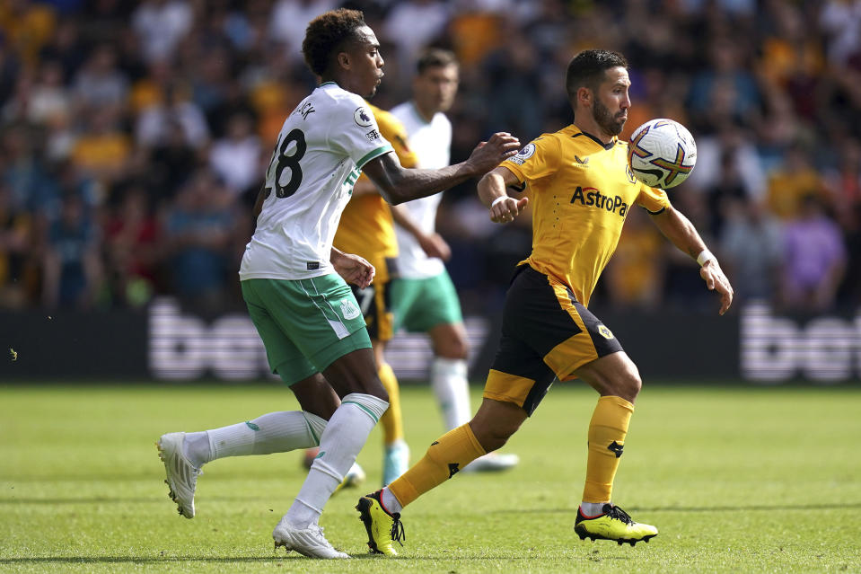 Newcastle United's Joe Willock, left, and Wolverhampton Wanderers' Joao Moutinho battle for the ball during the Premier League match between Wolverhampton Wanderers and Newcastle United at the Molineux Stadium, Wolverhampton, Britain, Sunday Aug. 28, 2022. (Jacob King/PA via AP)