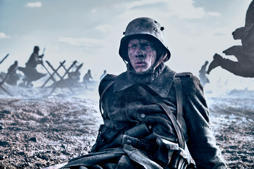 Still from All Quiet on the Western Front WWI soldier sits on a muddy battlefield