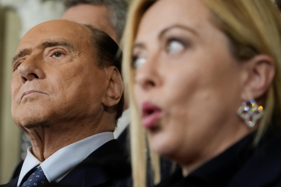 Forza Italia leader Silvio Berlusconi, left, listens to Brothers of Italy's leader Giorgia Meloni talking to journalists at the Quirinale Presidential Palace after a meeting with Italian President Sergio Mattarella as part of a round of consultations with party leaders to try and form a new government, in Rome, Friday, Oct. 21, 2022. (AP Photo/Gregorio Borgia)