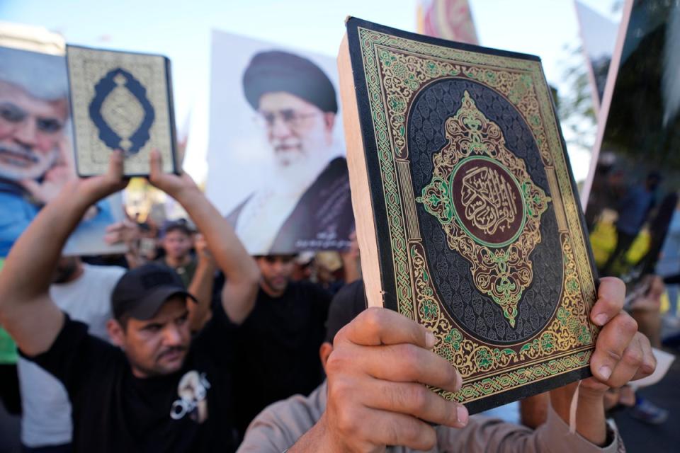 Iraqis raise copies of the Quran during a protest in Baghdad (AP)