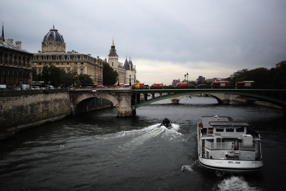 Rescue vehicles park on the bridge leading to the Paris police headquarters, left, Thursday, Oct.3, 2019. A union official says 4 police officers have died in a knife attack by an employee at Paris police headquarters. (AP Photo/Kamil Zihnioglu)