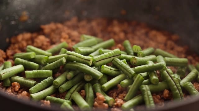 Adding long beans to frying pan