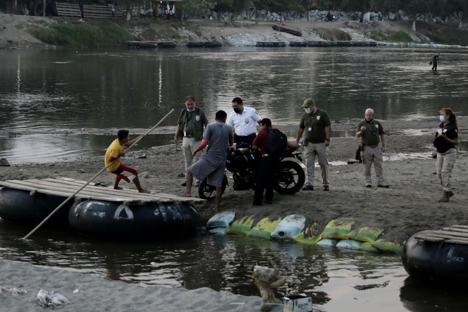 Mexican immigration agents review the IDs of Guatemalan merchants at an access point to the Suchiate River, the natural border between Guatemala and Mexico, near Ciudad Hidalgo, Mexico, Sunday, March 21, 2021. Mexico sent hundreds of immigration agents, police and National Guard to its southern border to launch an operation to crack down on migrant smuggling. (AP Photo/Eduardo Verdugo)