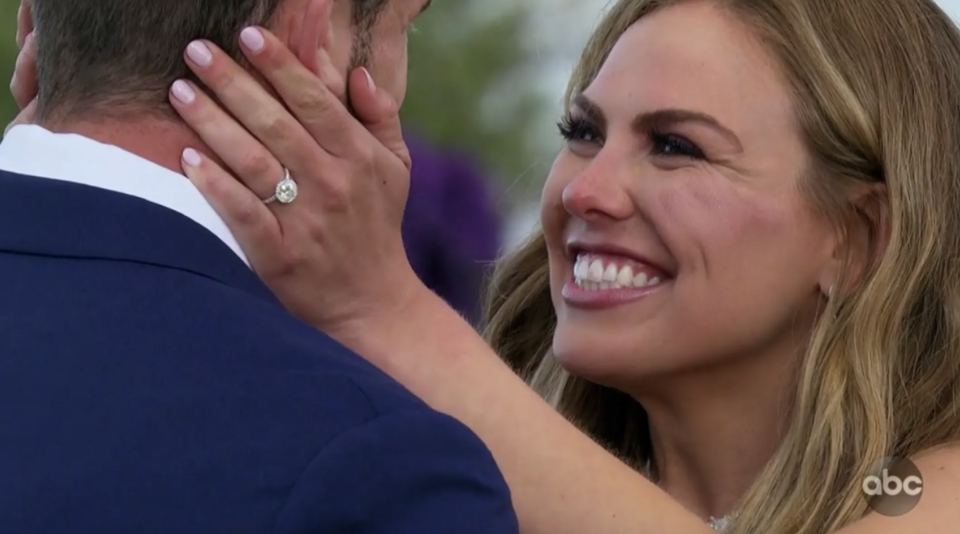 a woman holding her fiance's face with her engagement ring showing