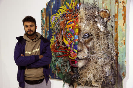 Street artist Bordalo II poses next to one of his creation "Half Lion" (2018) prior to the opening of his exhibition in Paris, France, January 22, 2019. Picture taken January 22, 2019. REUTERS/Philippe Wojazer