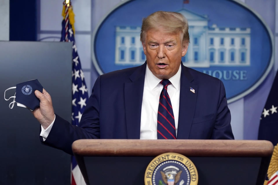 President Donald Trump holds a face mask as he speaks during a news conference at the White House, Tuesday, July 21, 2020, in Washington. (AP Photo/Evan Vucci)