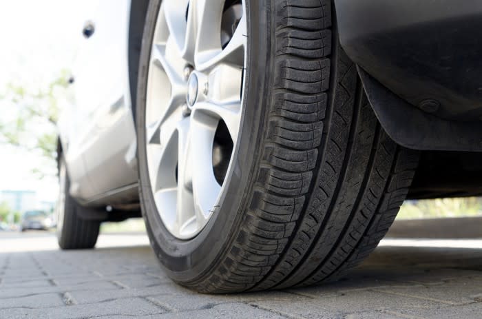 Close-up of a car tire on brick pavers.