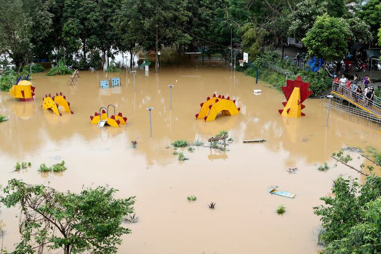 Personas observan una estructura en forma de dragón que quedó sumergida en un parque tras el paso del tifón Yagi, el martes 10 de septiembre de 2024, en Hanói, Vietnam. (AP Foto/Huy Han)