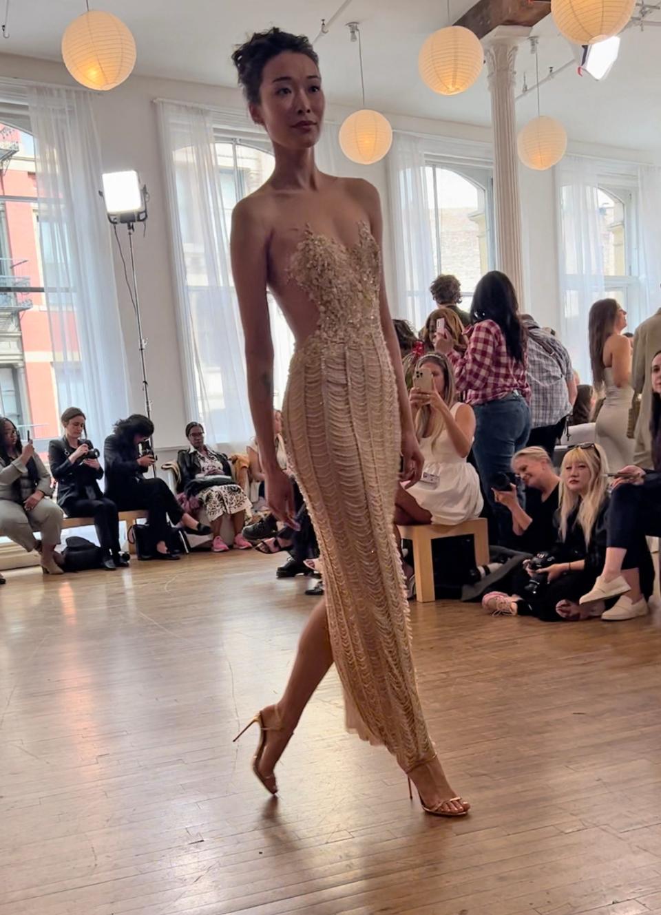 A woman poses in a form-fitting wedding dress with side cutouts.