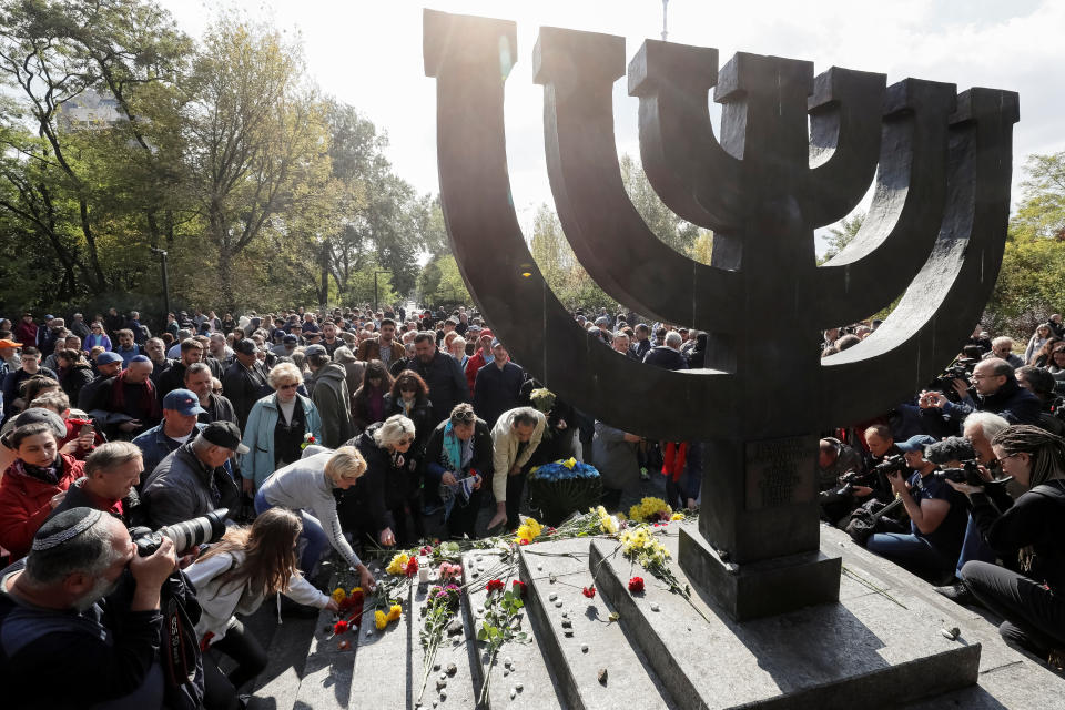 People place flowers during a ceremony at a monument commemorating the victims of Babyn Yar (Babiy Yar), one of the biggest single massacres of Jews during the Nazi Holocaust, in Kiev, Ukraine September 29, 2019.  REUTERS/Gleb Garanich