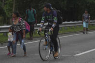 Migrants walk and cycle along the highway toward the municipality of Escuintla, Chiapas state, Mexico, early Thursday, Oct. 28, 2021, as they continue their journey toward the northern states of Mexico and the U.S. border. (AP Photo/Marco Ugarte)
