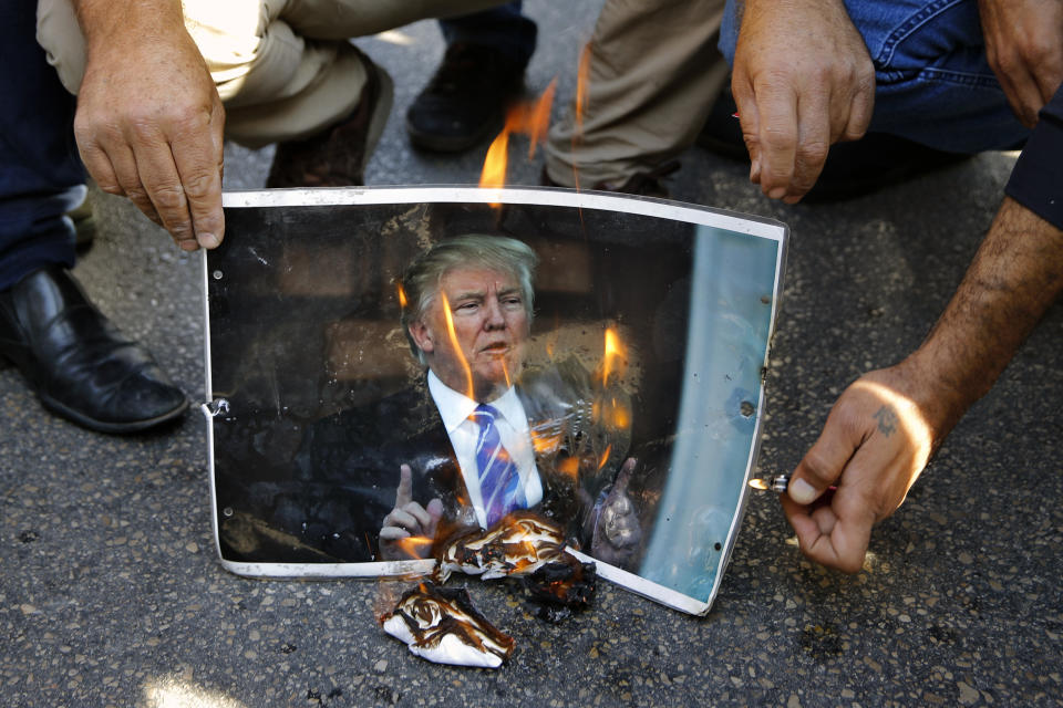 Demonstrators burn a poster of U.S. President Donald Trump during a protest by few dozen people against what they called, "America's intervention in Lebanon's affairs," near the U.S. embassy in Aukar, northeast of Beirut, Lebanon, Sunday, Nov. 24, 2019. Lebanese troops and riot police took tight measures Sunday near the embassy. (AP Photo/Bilal Hussein)