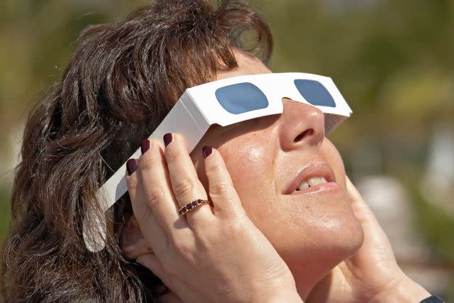 <p>Getty</p> Stock image of a woman looking through solar eclipse glasses