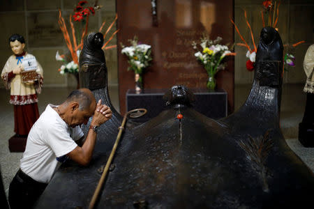 A man prays by the grave of slain Salvadoran archbishop Oscar Arnulfo Romero in San Salvador, El Salvador, March 7, 2018. REUTERS/Jose Cabezas