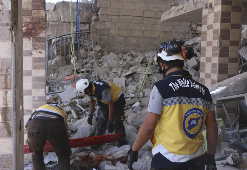 This photo provided by the Syrian Civil Defense White Helmets, which has been authenticated based on its contents and other AP reporting, shows Syrian White Helmet civil defense workers search for victims from under the rubble of a destroyed building that hit by Syrian government and Russian airstrikes, in the northern town of Maaret al-Numan, in Idlib province, Syria, Monday, July 22, 2019. Syrian opposition activists say an airstrike on a busy market in a rebel-held town in northwestern Syria has killed at least 16 people. (Syrian Civil Defense White Helmets via AP)