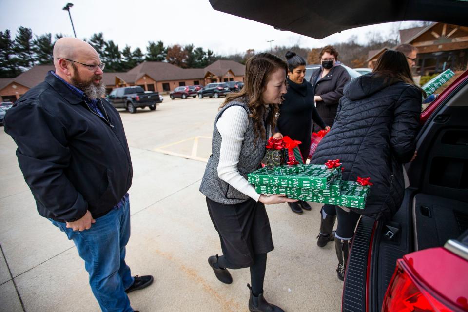 Emily Koszyk with Homes for Heroes helps load gifts for Aaron and Claudine Miller Tuesday, Dec. 7, 2021 at McKinnies Realty in Mishawaka.