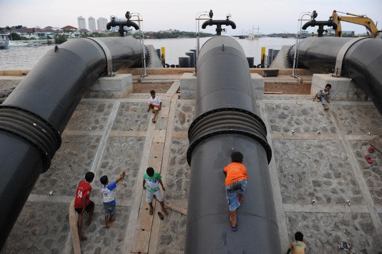 Children residing in the slum area play along a dyke as construction of the Jakarta sea wall begins, October 9, 2014