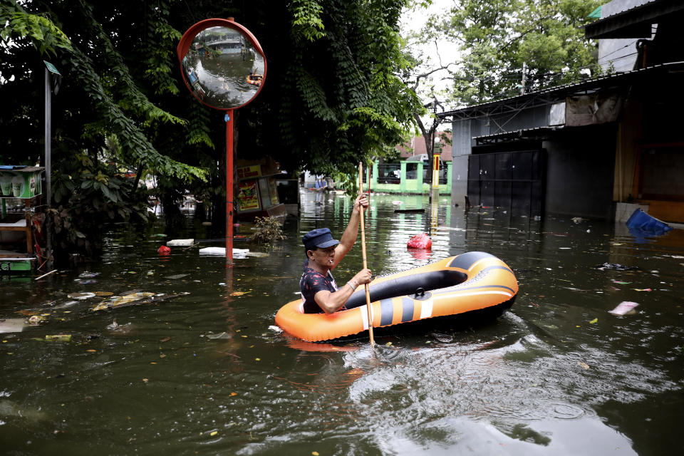 A man navigates an inflatable boat at a flooded neighborhood in Jakarta, Indonesia, Saturday, Jan. 4, 2020. Monsoon rains and rising rivers submerged parts of greater Jakarta and caused landslides in neighboring regions which buried a number of people. (AP Photo/Dita Alangkara)