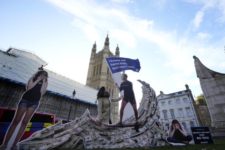 Senior campaigner from SumOfUs Flora Rebello Arduini adjusts an installation outside parliament in Westminster in London, Monday, Oct. 25, 2021. A 4-metre-high installation depicting Mark Zuckerberg surfing on a wave of cash was constructed outside parliament, as Facebook whistleblower Frances Haugen is due to testify to MPs on how the company puts profits ahead of public safety. The action comes after SumOfUs research revealed Instagram is still awash with posts promoting eating disorders, unproven diet supplements and skin-whitening products. (AP Photo/Kirsty Wigglesworth)