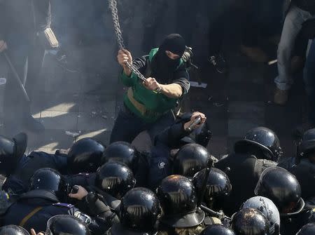 A radical protester clashes with law enforcement members on the Day of Ukrainian Cossacks, marked by activists and supporters of the All-Ukrainian Union Svoboda (Freedom) Party and far-right activists and nationalists to honour the role of the movement in the history of Ukraine, during a rally near the parliament building in Kiev, October 14, 2014. REUTERS/Gleb Garanich