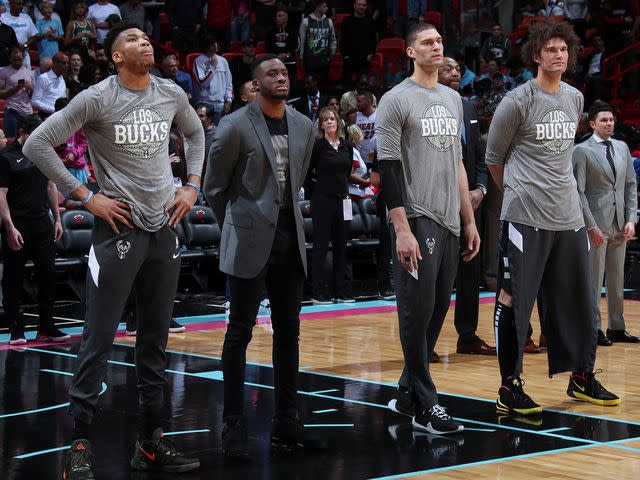 <p>Issac Baldizon/NBAE/Getty</p> Giannis Antetokounmpo, Thanasis Antetokounmpo, Brook Lopez and Robin Lopez stand for the National Anthem before the game against the Miami Heat on March 02, 2020.