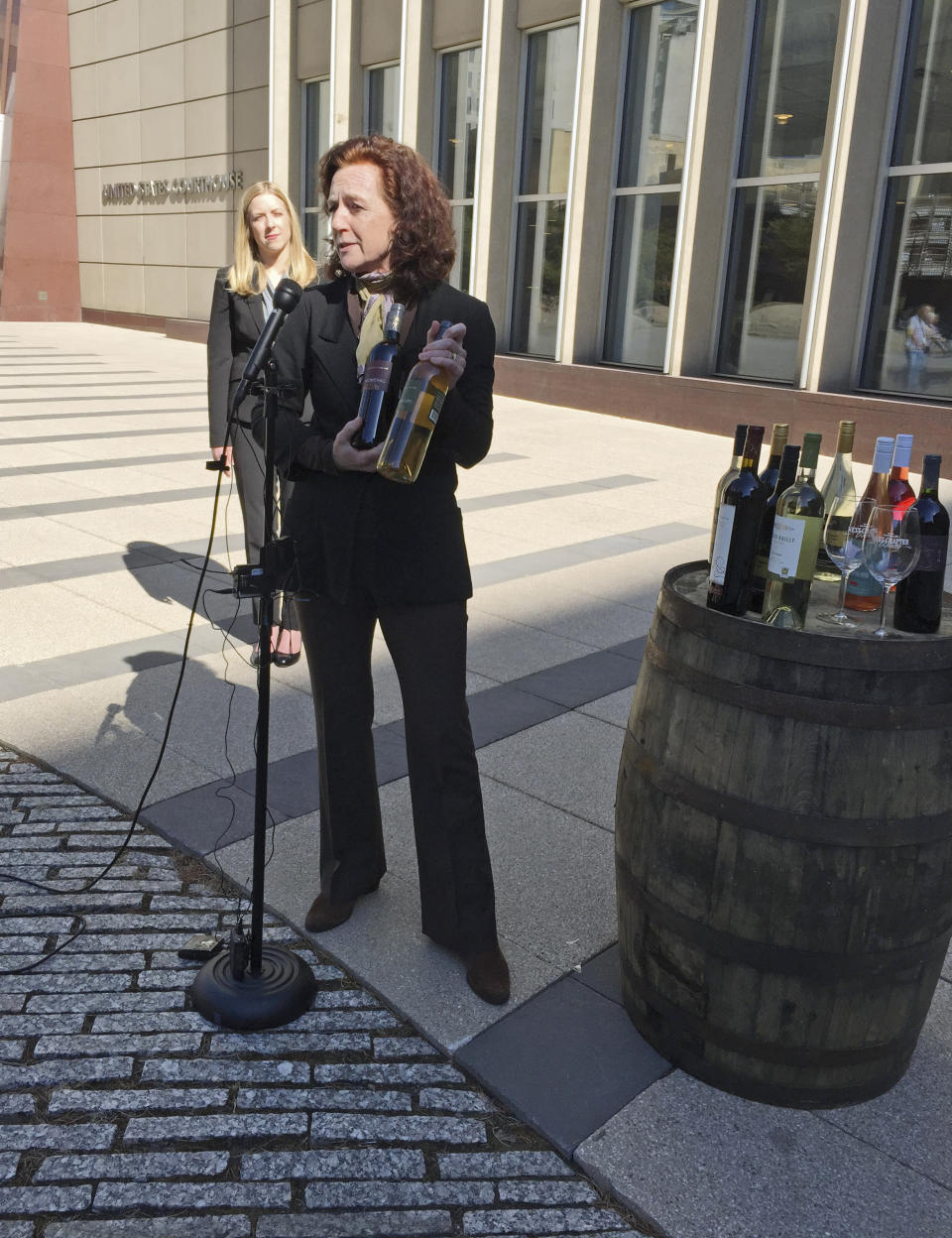 Nan Bailly, owner of Alexis Bailly Vineyard, of Hastings, Minn., with attorney Meagan Forbes in the background, holds bottles of wines from her winery at a news conference Tuesday, March 28, 2017, outside the federal courthouse in Minneapolis to announce a lawsuit seeking to overturn a law that requires them to make their products with a majority of grapes grown in Minnesota, a state that's better known for its winters than vineyards. (AP Photo/Steve Karnowski)