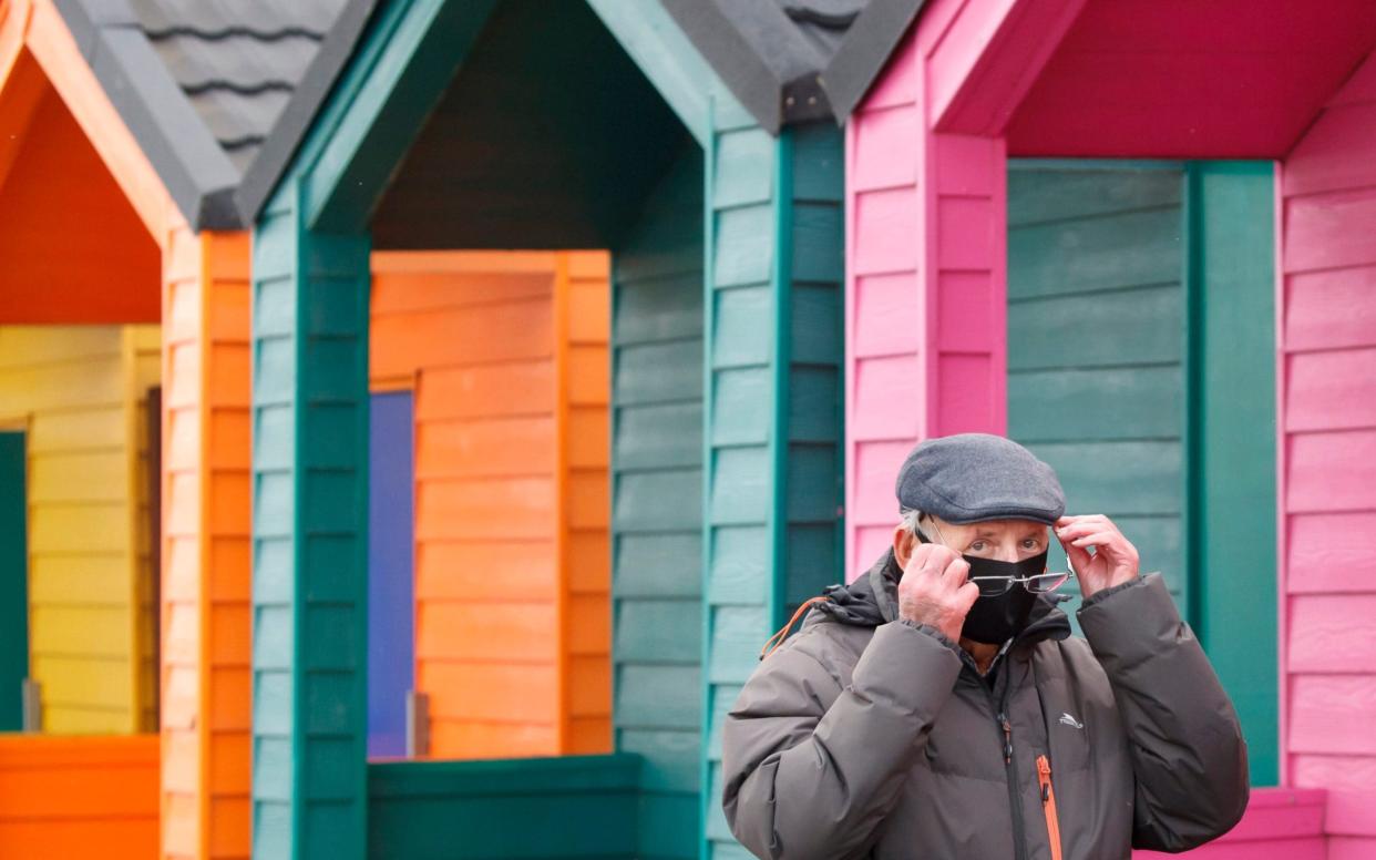 A man wears a face covering as he walks past beach huts in Saltburn-by-the-Sea - Danny Lawson / PA