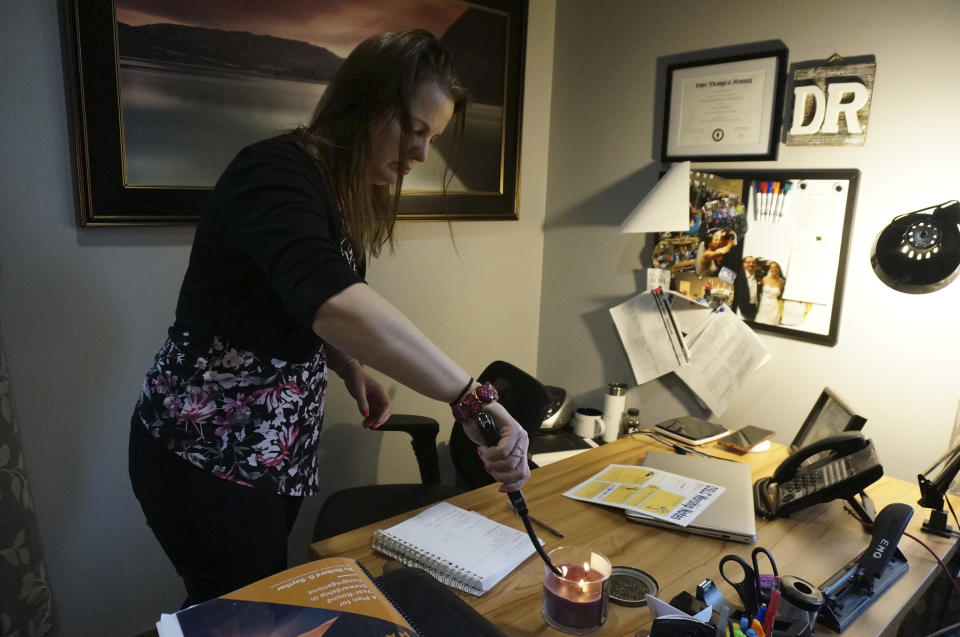 The Rev. Karna Moskalik lights a candle in her office at Our Savior's Lutheran Church in Stillwater, Minn., on Wednesday Sept. 27, 2023. Lighting a perfumed candle, praying, and meditating are all strategies she employs to ground her and be a more effective faith leader after doing doctoral research on resiliency. (AP Photo/Giovanna Dell'Orto)