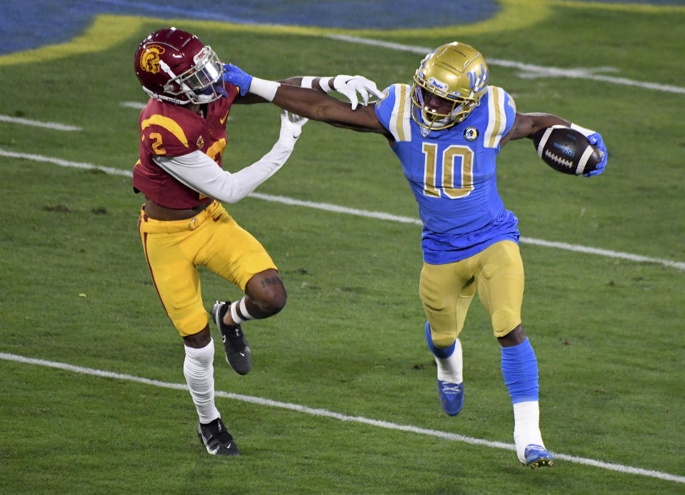 UCLA running back Demetric Felton, right, runs for a first down as Southern California's Olaijah Griffin defends during the first half of an NCAA college football game Saturday, Dec. 12, 2020, in Pasadena, Calif. (Keith Birmingham/The Orange County Register via AP)