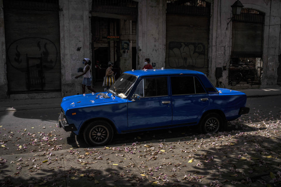 A Soviet-era Lada car is sprinkled in flowers after it parked under a tree on a street in Havana, Cuba, Friday, March 19, 2021. Maintenance of Lada cars is a trial. Owners manage to get some spare parts through “mules,” people who hand-carry goods into the island, but sometimes they must have parts made by hand. (AP Photo/Ramon Espinosa)