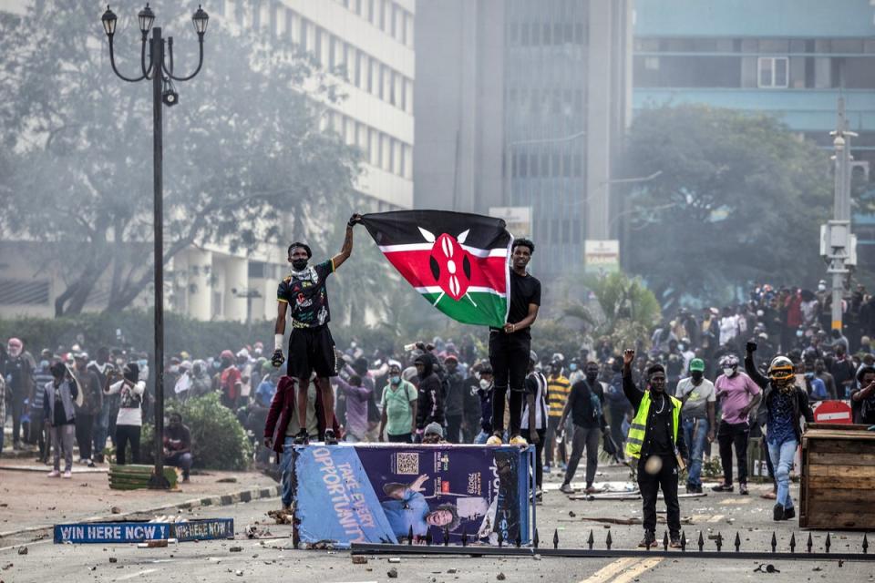 Protesters hold a Kenyan flag outside the Kenyan Parliament after storming the building during a nationwide protest against a tax bill (AFP via Getty Images)