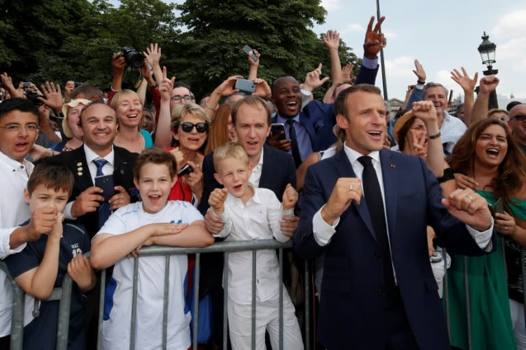 French President Emmanuel Macron joins a crowd shouting support for France on the eve of the World Cup final