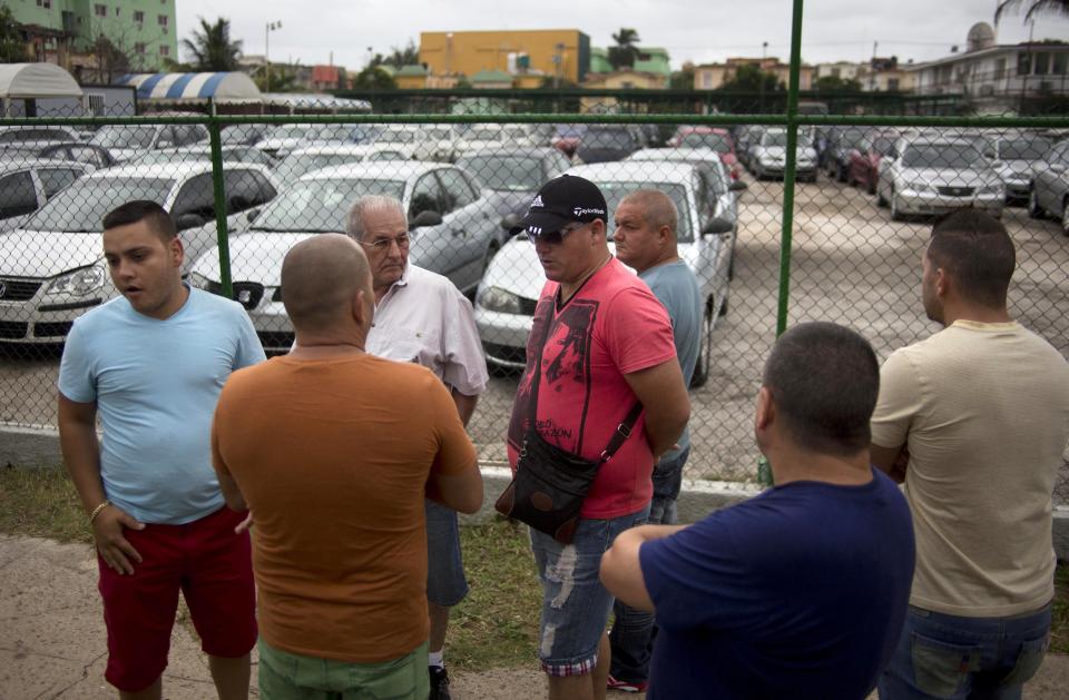 People gather outside a government-run car dealership that sells used vehicles in Havana, Cuba, Friday, Jan. 3, 2014. Cubans are eagerly visiting car dealerships as a new law takes effect on Friday eliminating a special permit requirement that has greatly restricted vehicle ownership in the country. To their dismay they found sharply hiked prices on the first day the law was in force. In Cuba, the government retains its monopoly on a vehicle's market value. (AP Photo/Ramon Espinosa)