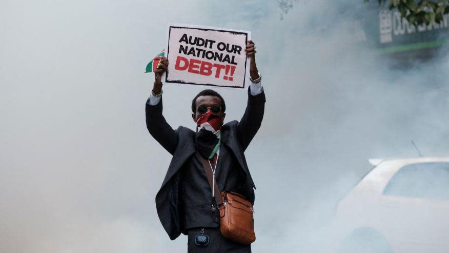 A protester holds a placard as a cloud of teargas surrounds him during an anti-government protests in Nairobi on July 16, 2024