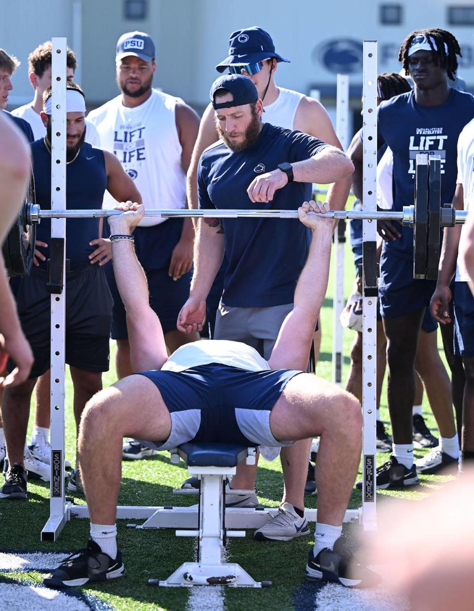 Penn State’s Nick Tarburton (on bench) does bench presses during the Nittany Lions annual Lift For Life event at University Park Thursday, June 30, 2022.