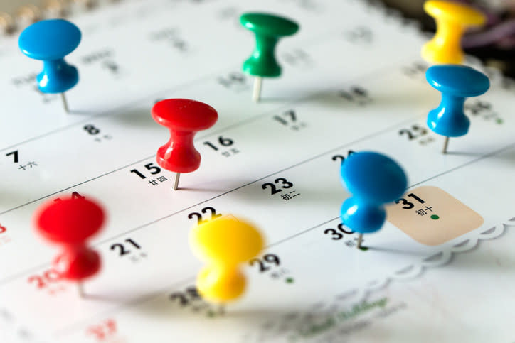 A calendar with many colored thumb tacks in it