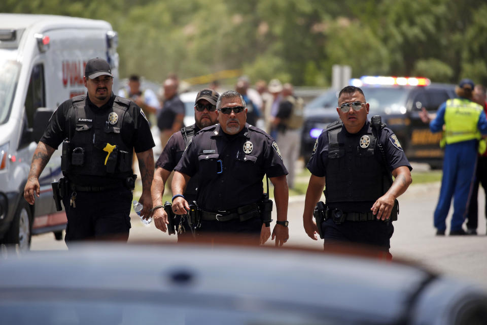 FILE - Police walk near Robb Elementary School following a shooting, Tuesday, May 24, 2022, in Uvalde, Texas. A gunman fatally shot 19 children and two teachers at the school. Over an hour passed from the time officers followed the 18-year-old gunman into the school and when they finally entered the fourth grade classroom where he was holed up and killed him. Meanwhile, students trapped inside repeatedly called 911 and parents outside the school begged officers to go in. On July 17, 2022, a damning report on the response was released by an investigative committee from the Texas House of Representatives as well as hours of body camera footage, further laying bare the chaotic response that included 376 officers. (AP Photo/Dario Lopez-Mills, File)