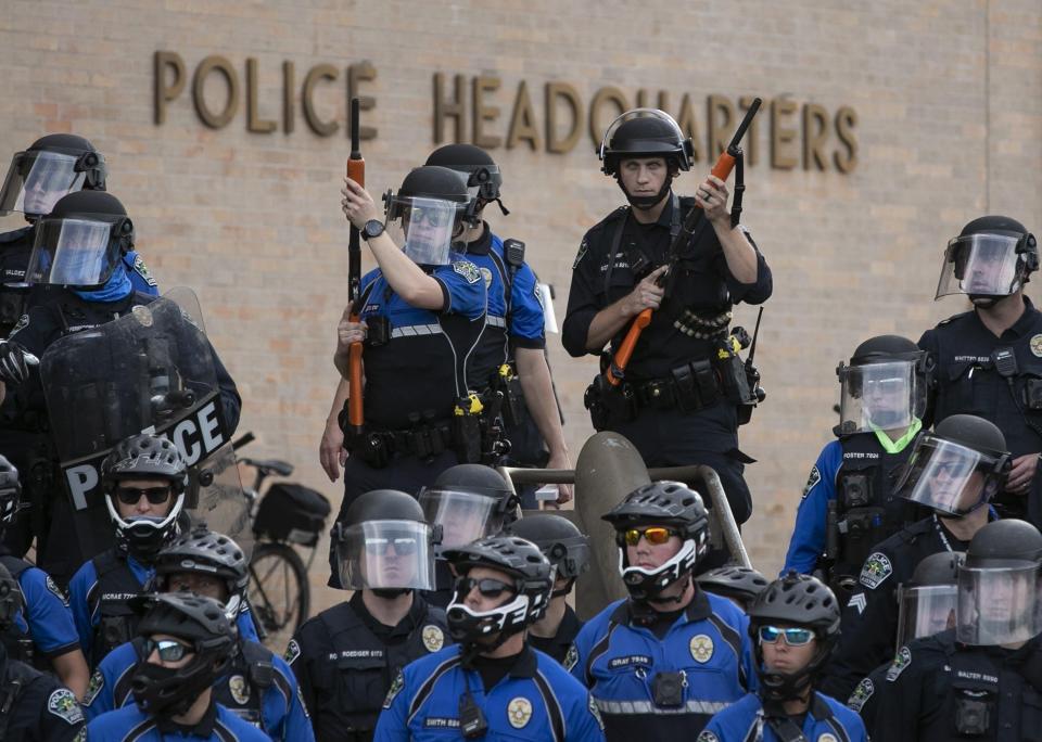 Police officers guard the Austin Police Department's headquarters during a social justice protest in May 2020. The city of Austin has settled another lawsuit with a woman who said police used excessive force against her during an August 2020 protest.