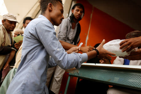 FILE PHOTO: A man displaced from Yemen's Red Sea city of Hodeidah receives food ration from a charity food distribution in Sanaa, Yemen July 3, 2018. REUTERS/Khaled Abdullah