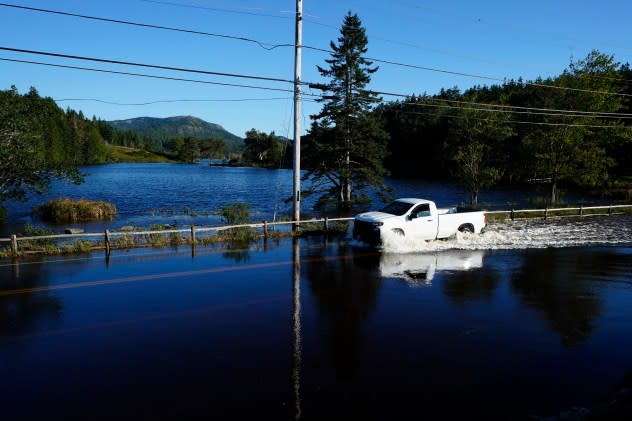 A motorist travels through flood waters on a road that remains closed a day after storm Lee passed through the region, Sunday, Sept. 17, 2023, near Northeast Harbor, Maine. (AP Photo/Robert F. Bukaty)