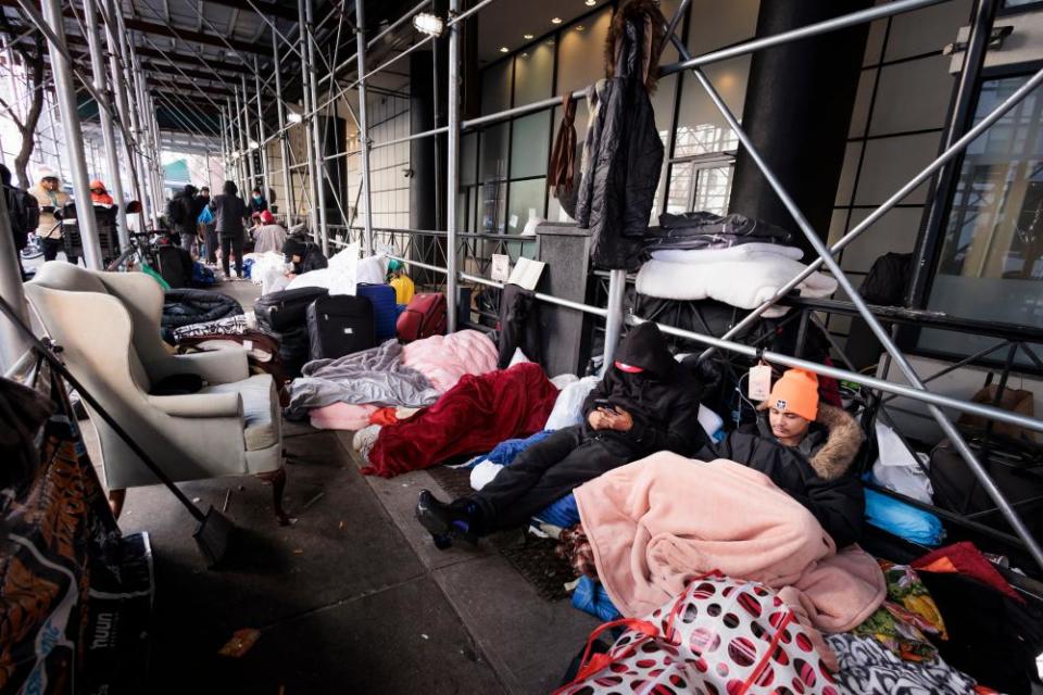 Migrants sit among their belongings outside of The Watson Hotel on West 57th Street in Manhattan.