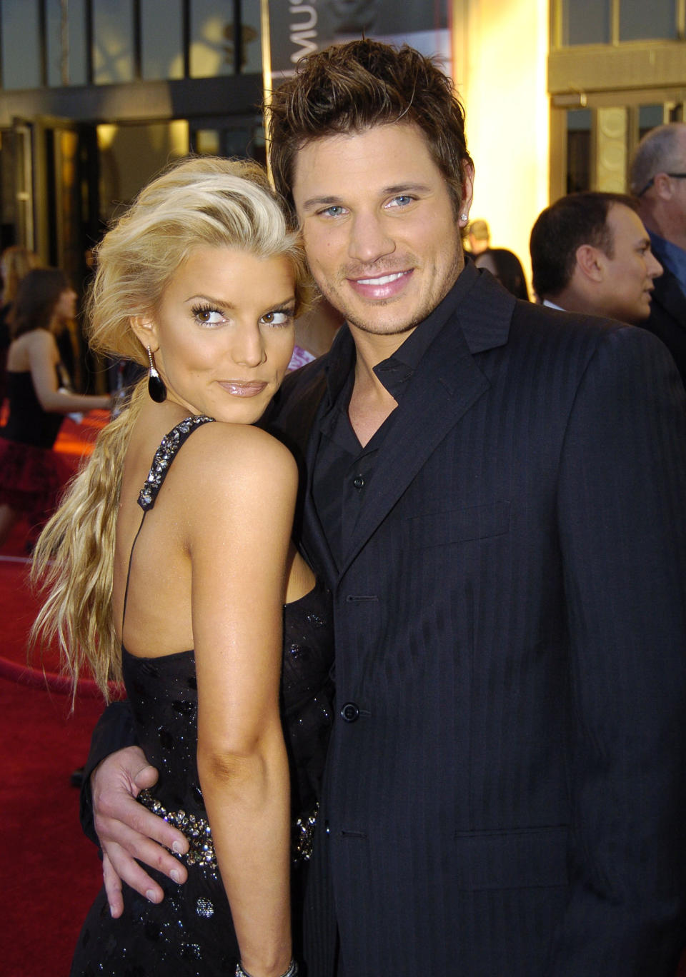 On the red carpet, he's smiling and has his arm around her waist; she's wearing a shiny sleeveless, low-back outfit