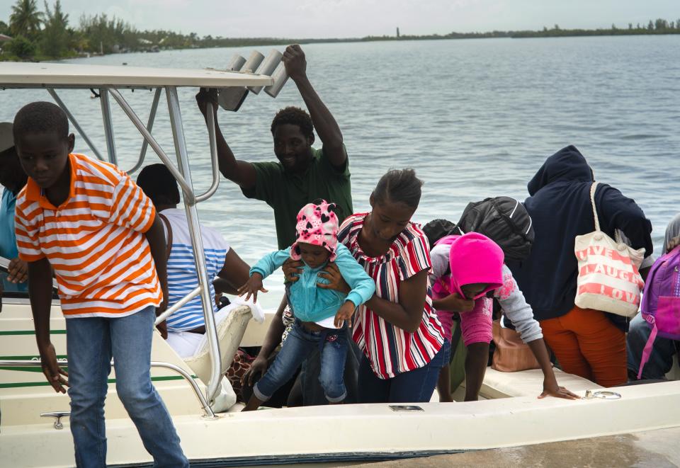 A woman carries a girl in her arms after being evacuated from a nearby Cay due to the danger of floods after arrive on a ship at the port before the arrival of Hurricane Dorian in Sweeting's Cay, Grand Bahama, Bahamas, Saturday Aug. 31, 2019. Dorian bore down on the Bahamas as a fierce Category 4 storm Saturday, with new projections showing it curving upward enough to potentially spare Florida a direct hit but still threatening parts of the Southeast U.S. with powerful winds and rising ocean water that causes what can be deadly flooding. (AP Photo/Ramon Espinosa)