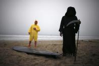 Sean Owolo, 40, (R) dressed as the Grim Reaper, and Marius Petrulis, 36, dressed as a chicken, prepare to compete in the ZJ Boarding House Halloween Surf Contest in Santa Monica, California October 26, 2013. REUTERS/Lucy Nicholson (UNITED STATES - Tags: TPX IMAGES OF THE DAY SPORT SOCIETY)