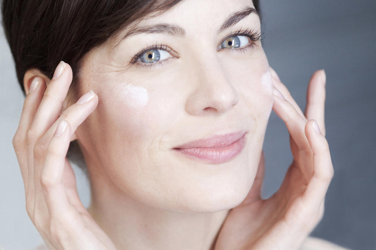 Woman applying cream on her face.