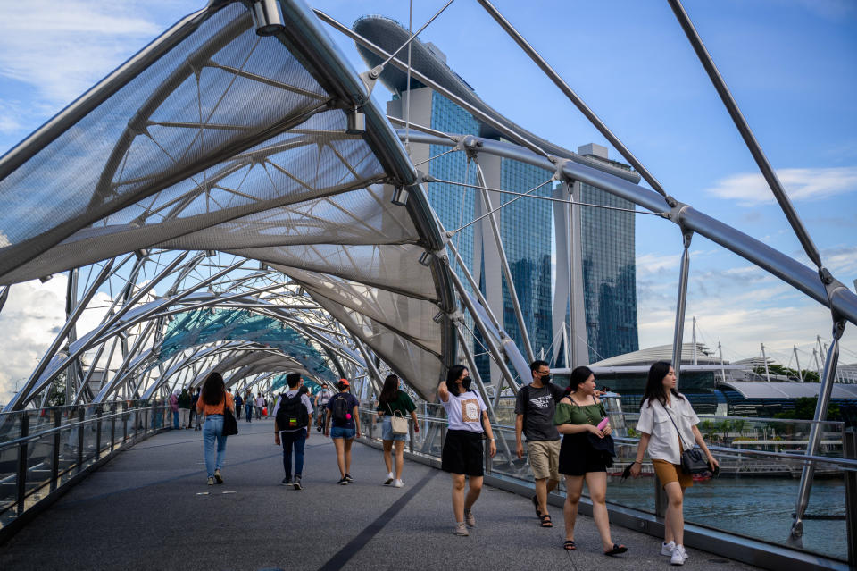 Pedestians cross a bridge in the scenic Marina Bay area in SIngapore.