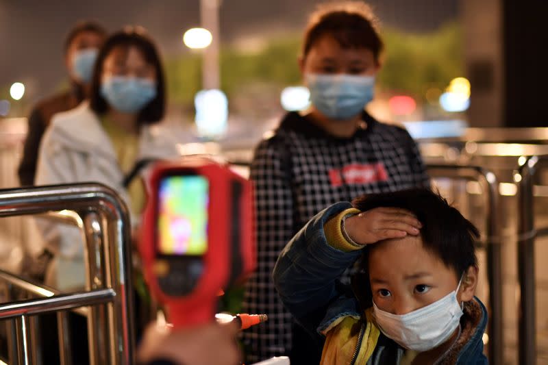 Child has his body temperature taken outside Hankou Railway Station in Wuhan