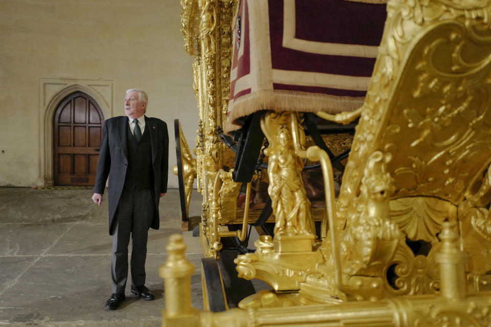 Britain's Speaker of the House of Commons Lindsay Hoyle poses next to the Speaker's State Coach as it returns to Westminster, ahead of the coronation of Britain's King Charles III, in London, Sunday, April 30, 2023. The gilded coach, which was last seen in the historic Westminster Hall in 2005, will be on display once again from 2 May to the Autumn, to commemorate the crowning of King Charles III. (AP Photo/Alberto Pezzali)