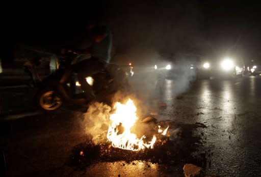 A tire burns as Lebanese relatives of those abducted in Syria block the road leading to Beirut's International Airport, calling for their release